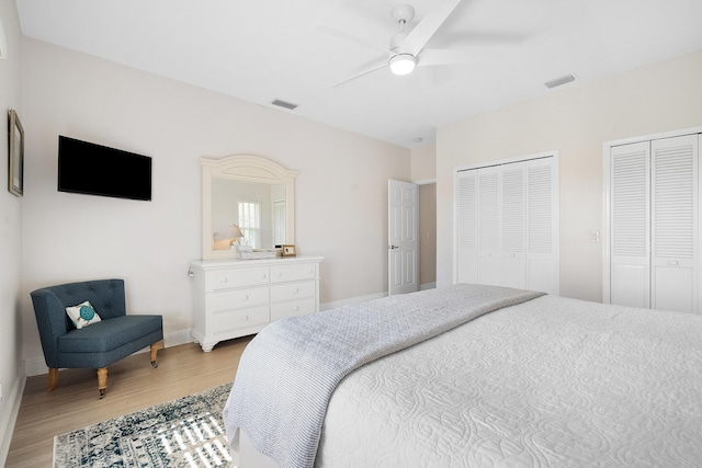 bedroom featuring multiple closets, ceiling fan, and light hardwood / wood-style flooring