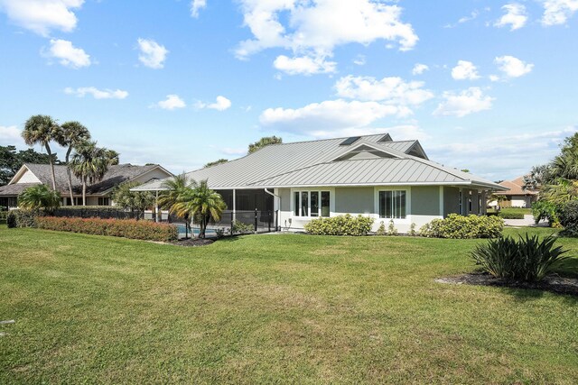 rear view of house featuring a sunroom and a lawn