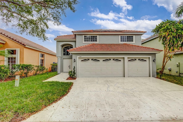 mediterranean / spanish home featuring a garage and a front yard