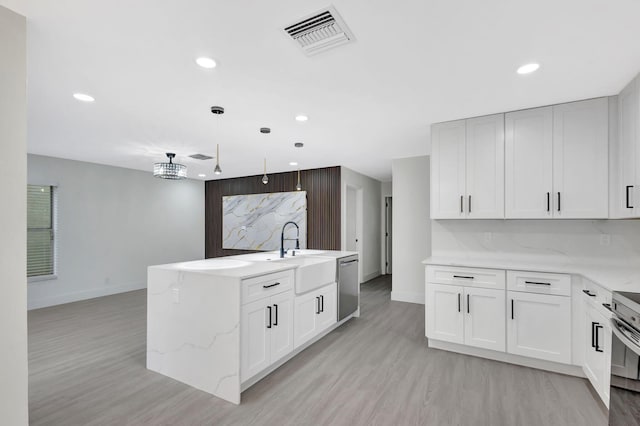 kitchen featuring white cabinetry, appliances with stainless steel finishes, a kitchen island with sink, and decorative light fixtures