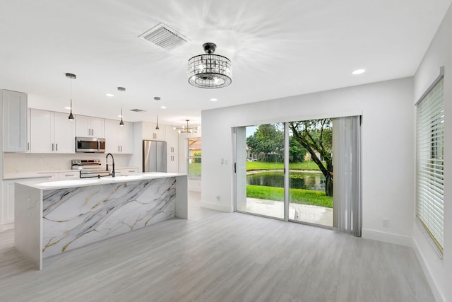 kitchen with light hardwood / wood-style flooring, stainless steel appliances, a center island, decorative light fixtures, and a chandelier