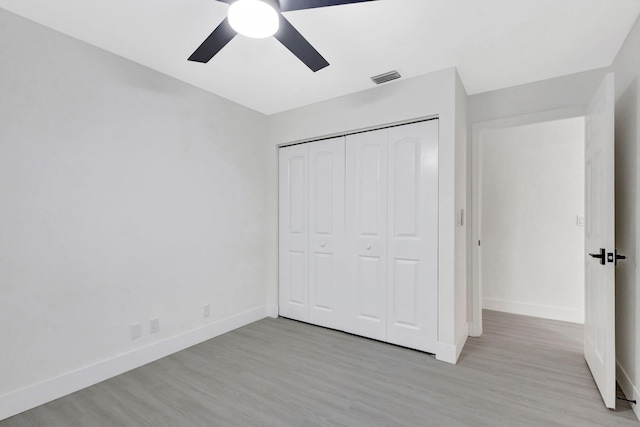 unfurnished bedroom featuring ceiling fan, light hardwood / wood-style floors, and a closet