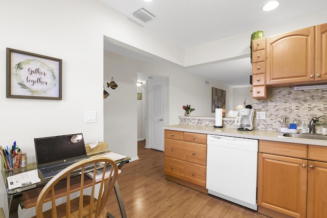 kitchen with white dishwasher, sink, backsplash, and light hardwood / wood-style flooring