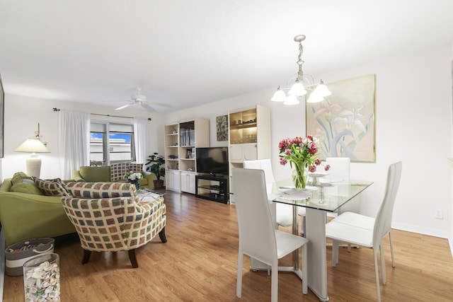 dining area with ceiling fan with notable chandelier and light wood-type flooring