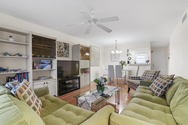 living room featuring ceiling fan with notable chandelier and light hardwood / wood-style flooring