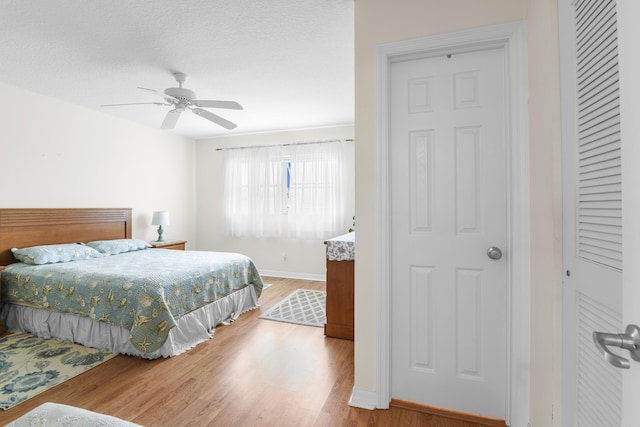 bedroom with hardwood / wood-style flooring, a textured ceiling, and ceiling fan