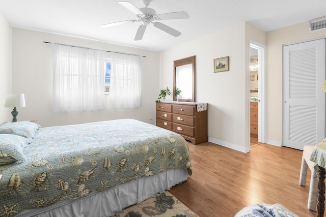 bedroom with ceiling fan, light hardwood / wood-style floors, ensuite bath, and a closet