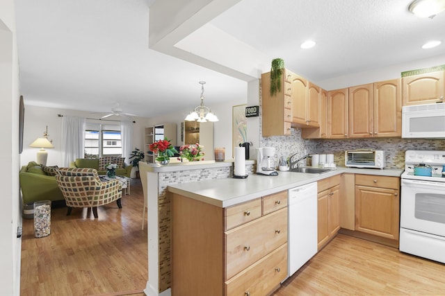 kitchen featuring light hardwood / wood-style floors, white appliances, decorative light fixtures, and kitchen peninsula