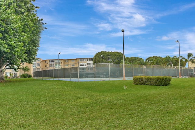 view of tennis court with a yard