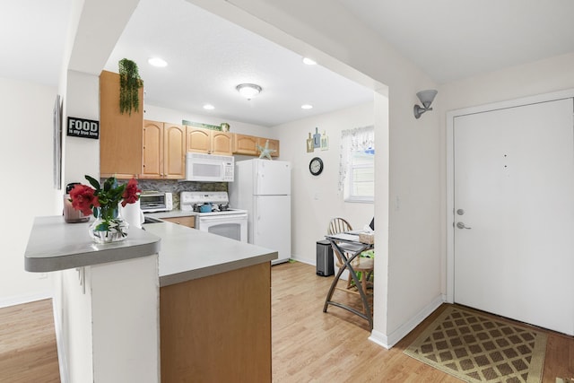 kitchen with tasteful backsplash, light wood-type flooring, a kitchen breakfast bar, kitchen peninsula, and white appliances