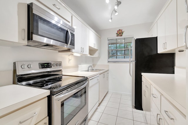 kitchen featuring sink, light tile patterned floors, stainless steel appliances, and white cabinets