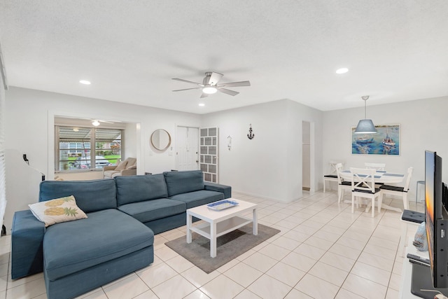 living room featuring ceiling fan, light tile patterned floors, and a textured ceiling