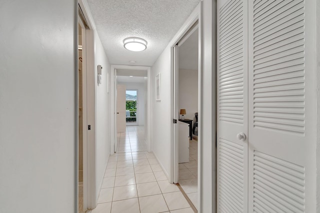 corridor with light tile patterned flooring and a textured ceiling