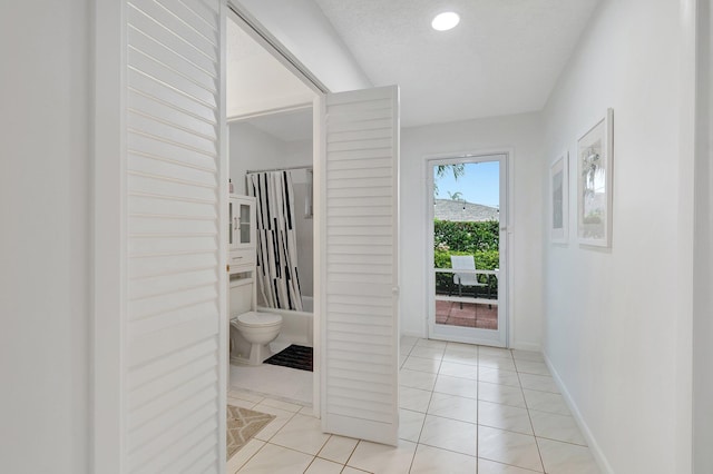 hall with light tile patterned floors and a textured ceiling