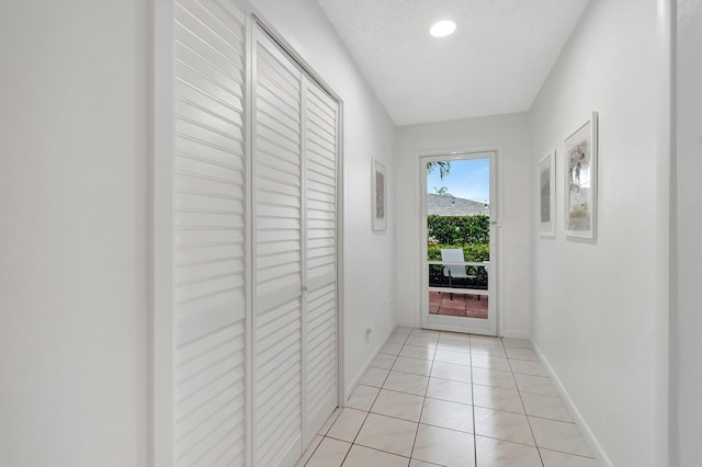 hallway with a textured ceiling and light tile patterned floors