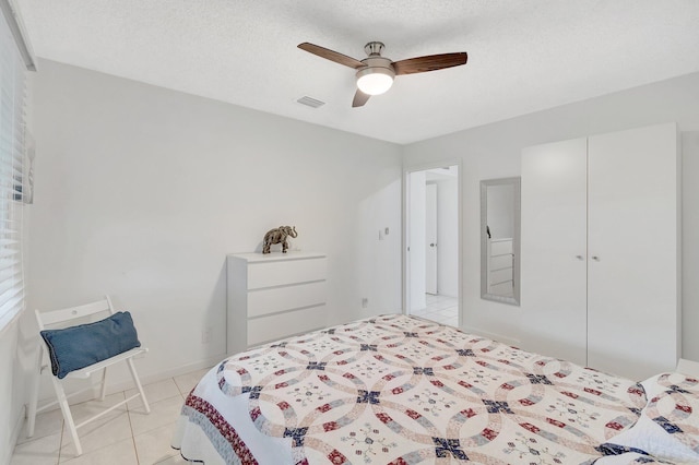 bedroom with light tile patterned floors, a textured ceiling, and ceiling fan