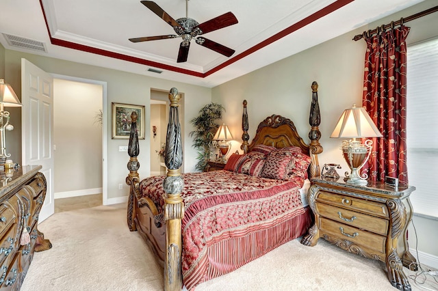 bedroom with ceiling fan, ornamental molding, a raised ceiling, and light colored carpet