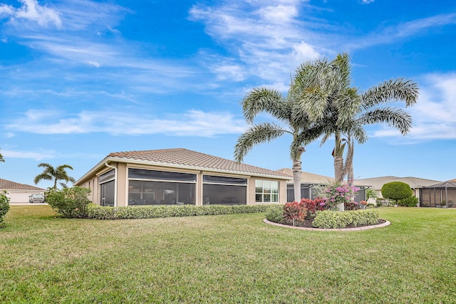 back of property with a sunroom and a lawn