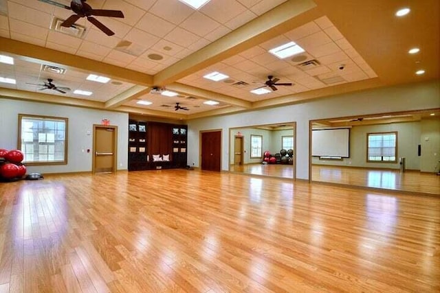 workout room featuring plenty of natural light, a paneled ceiling, ceiling fan, and light wood-type flooring