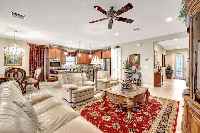 tiled living room with ceiling fan with notable chandelier and a textured ceiling