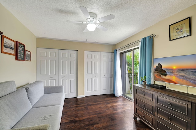 living room with ceiling fan, dark wood-type flooring, and a textured ceiling