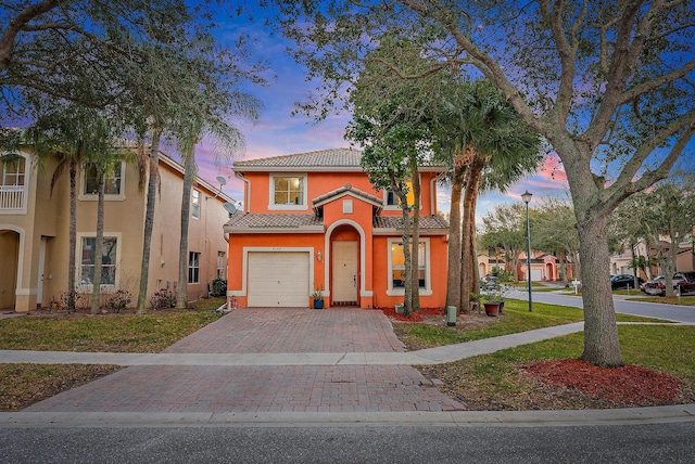 mediterranean / spanish-style home with a garage and a yard