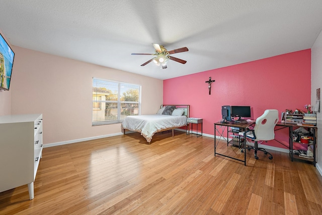 bedroom with ceiling fan, a textured ceiling, and light wood-type flooring