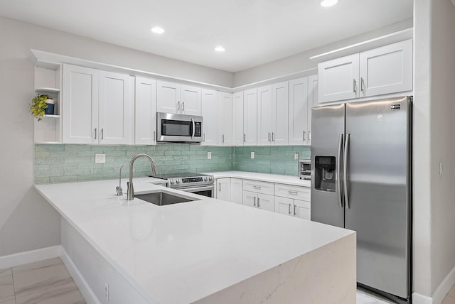 kitchen with sink, kitchen peninsula, stainless steel appliances, decorative backsplash, and white cabinets