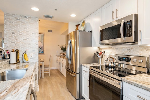 kitchen featuring tasteful backsplash, light stone countertops, appliances with stainless steel finishes, and white cabinets