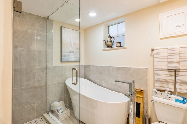 bathroom with tile walls, a washtub, tile patterned floors, and toilet