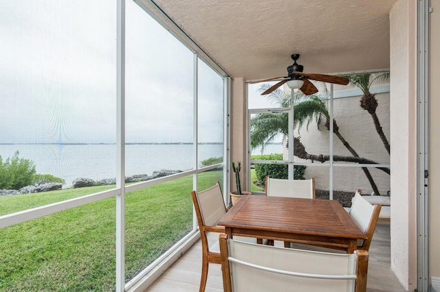 sunroom / solarium with a water view, ceiling fan, and plenty of natural light