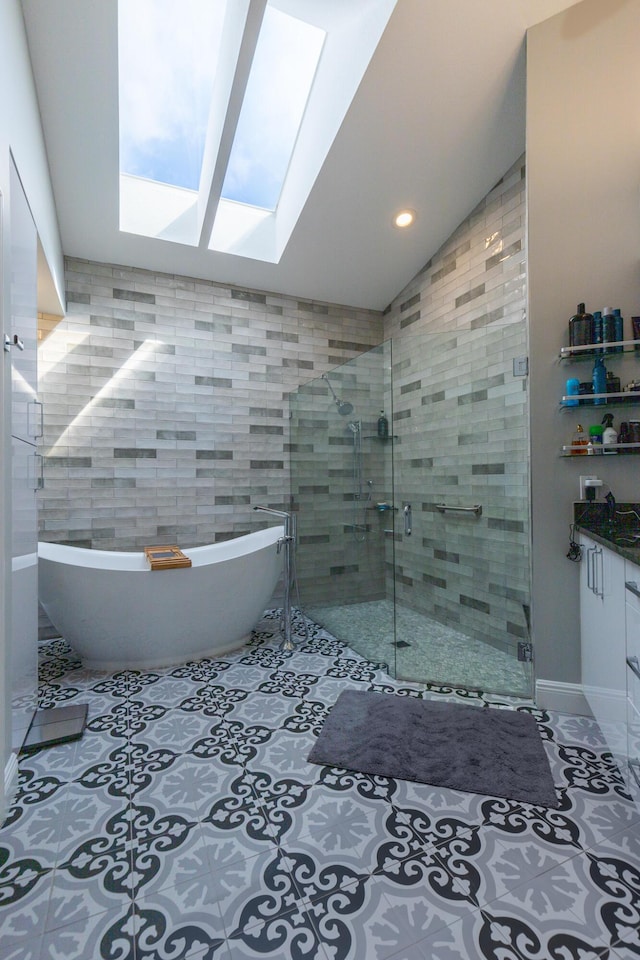 bathroom with vanity, a skylight, plus walk in shower, and tile walls