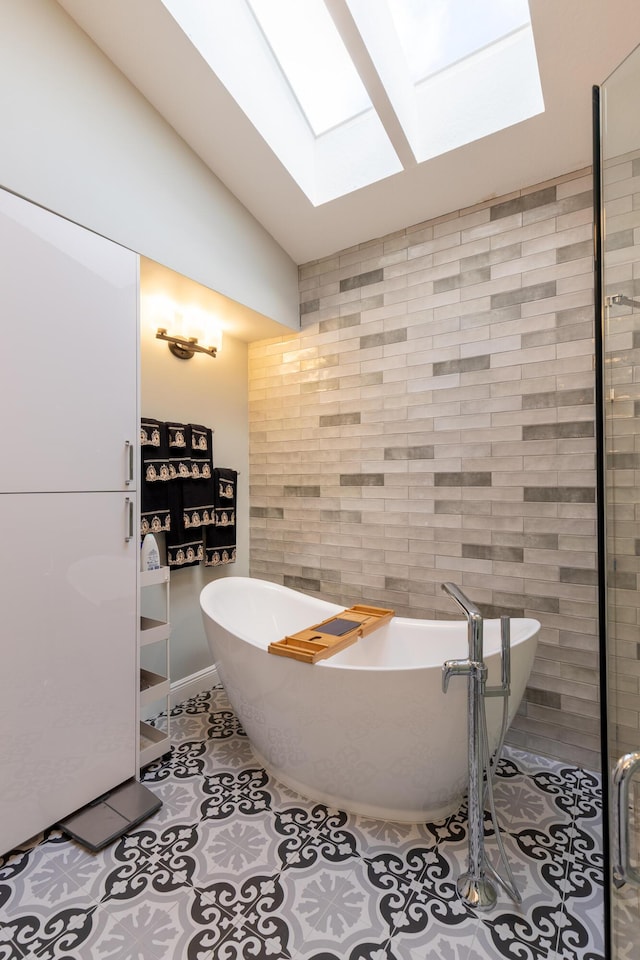 bathroom with vaulted ceiling with skylight, tile patterned flooring, and a tub