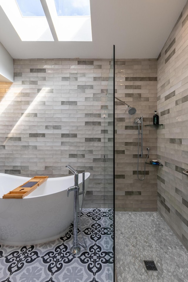 bathroom featuring shower with separate bathtub, tile walls, tile patterned floors, and a skylight