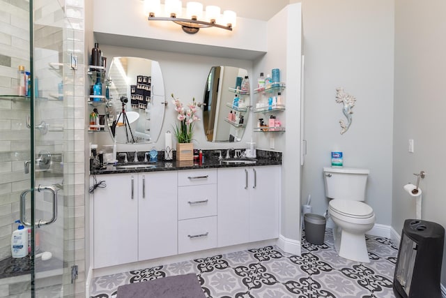 bathroom with tile patterned floors, vanity, toilet, and a shower with shower door