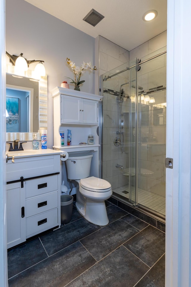 bathroom with toilet, vanity, and a shower with shower door