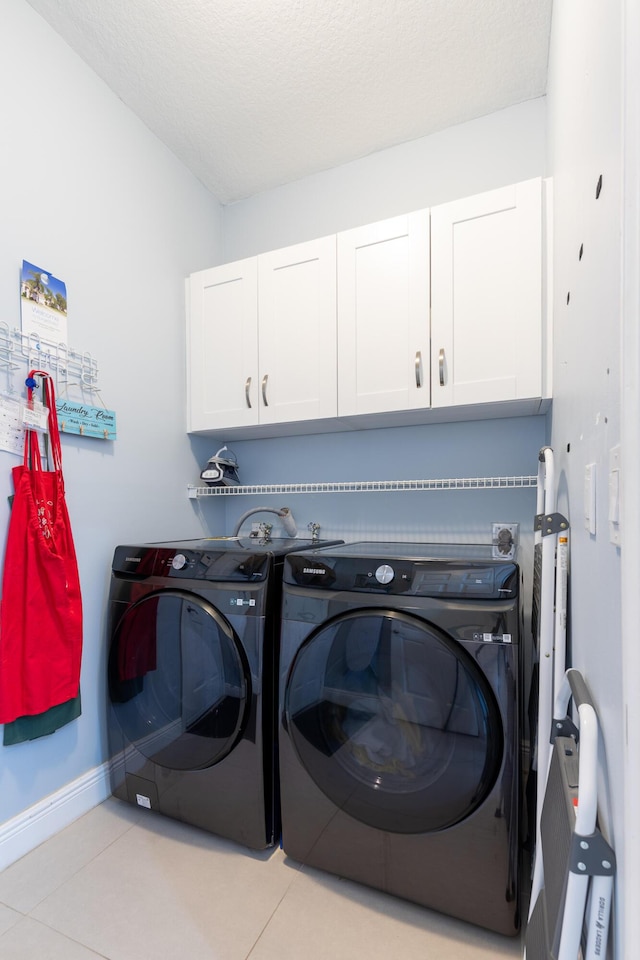 laundry room with independent washer and dryer, light tile patterned floors, cabinets, and a textured ceiling