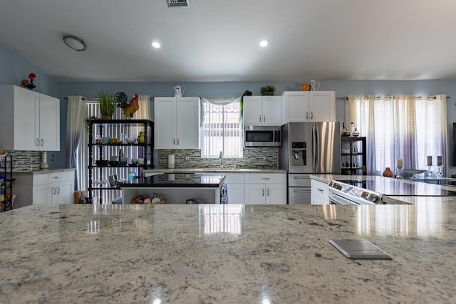 kitchen featuring tasteful backsplash, stainless steel appliances, and white cabinets