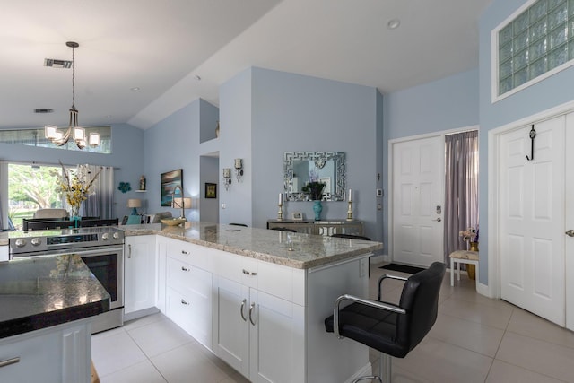 kitchen with light tile patterned floors, vaulted ceiling, white cabinetry, decorative light fixtures, and stainless steel electric stove