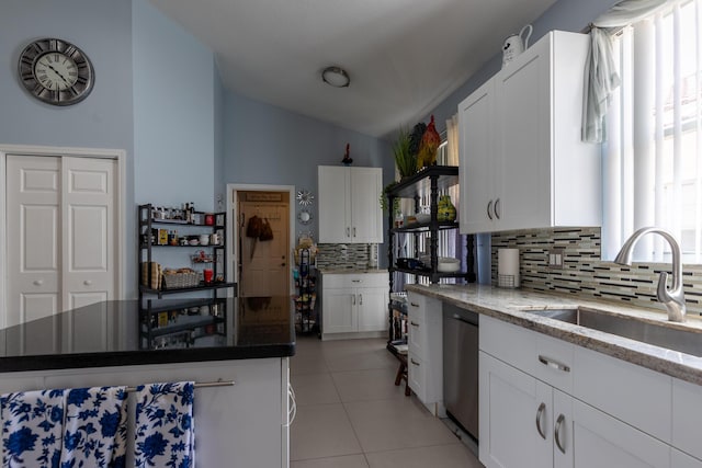 kitchen with tasteful backsplash, white cabinetry, sink, and stainless steel dishwasher