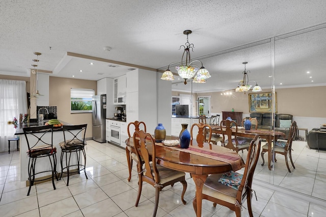 dining space with light tile patterned floors, crown molding, sink, and a textured ceiling