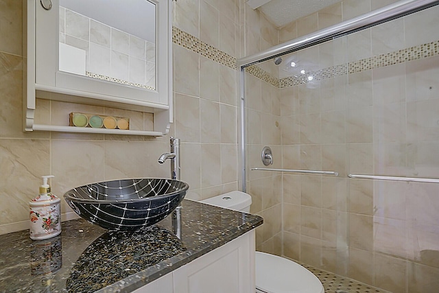 bathroom with sink, a shower with door, tile walls, backsplash, and toilet