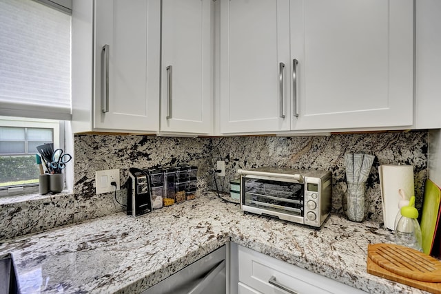 kitchen featuring tasteful backsplash, white cabinetry, and light stone counters