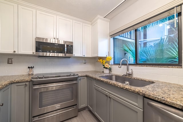 kitchen with white cabinetry, sink, light stone counters, and stainless steel appliances