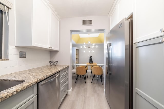 kitchen with backsplash, white cabinets, stainless steel appliances, light stone countertops, and light wood-type flooring