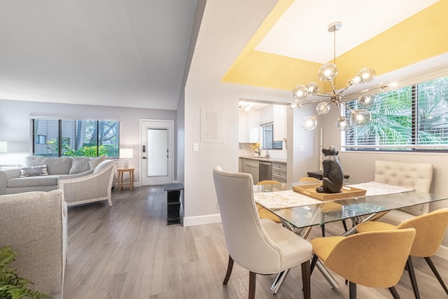 dining space with an inviting chandelier, sink, light hardwood / wood-style flooring, and vaulted ceiling