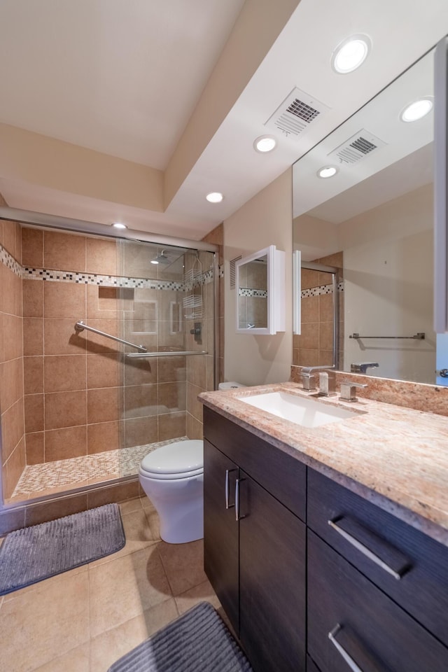 bathroom with tile patterned flooring, vanity, walk in shower, and toilet