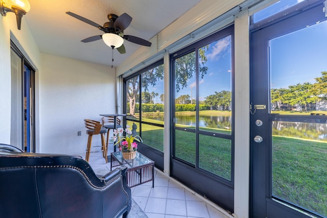 sunroom featuring a water view, ceiling fan, and plenty of natural light