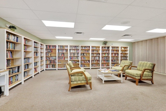 sitting room featuring a paneled ceiling, carpet, and wood walls