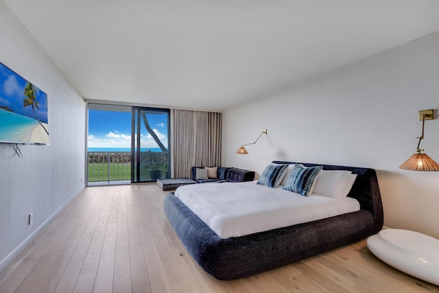 bedroom with access to outside, light hardwood / wood-style floors, and expansive windows